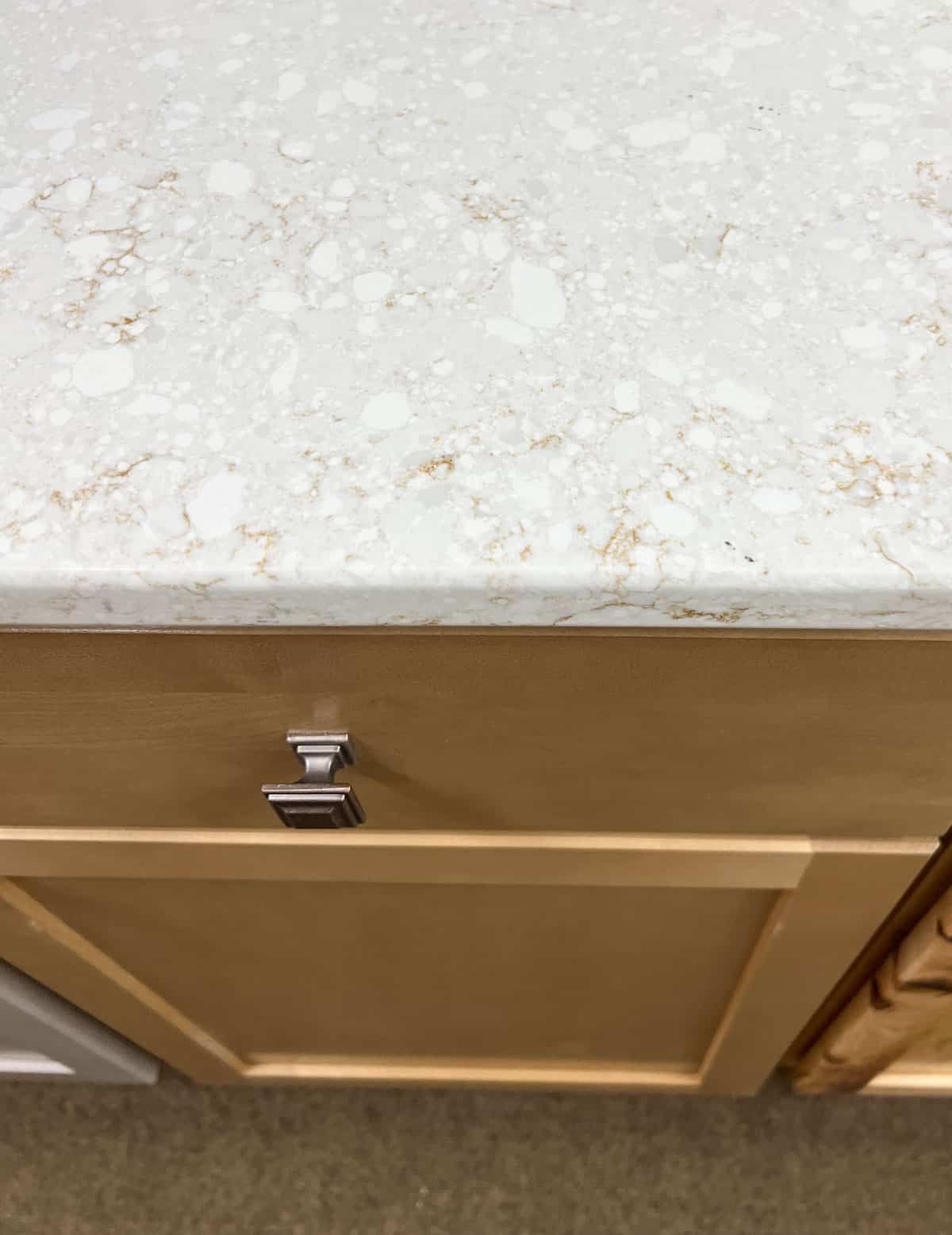 quartz white and beige countertop on yellow oak cabinets.