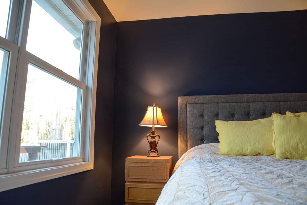 dark blue walls, with white windows and cream and yellow bedding.