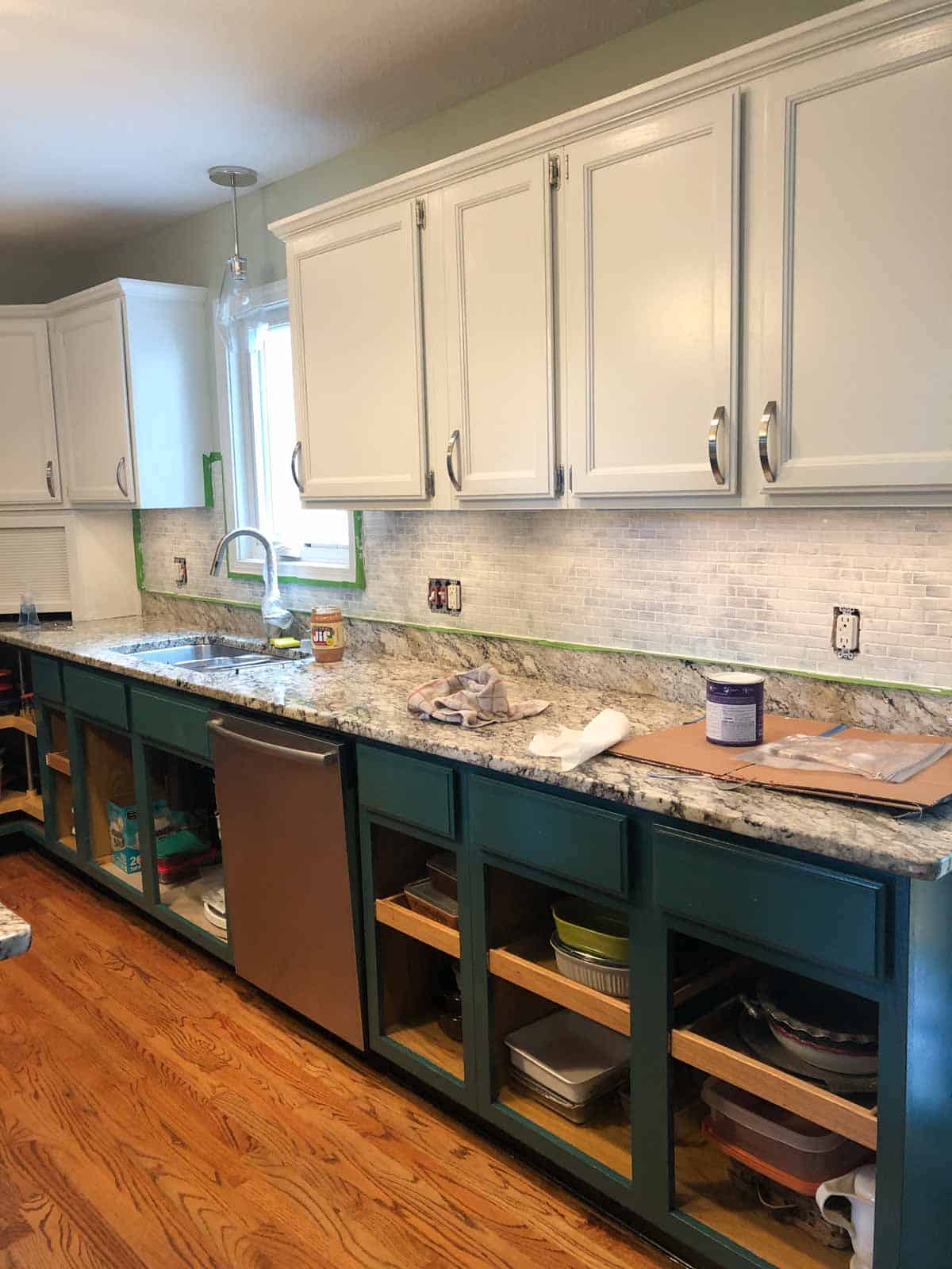 tile backsplash painted with white primer with green and white cabinets.